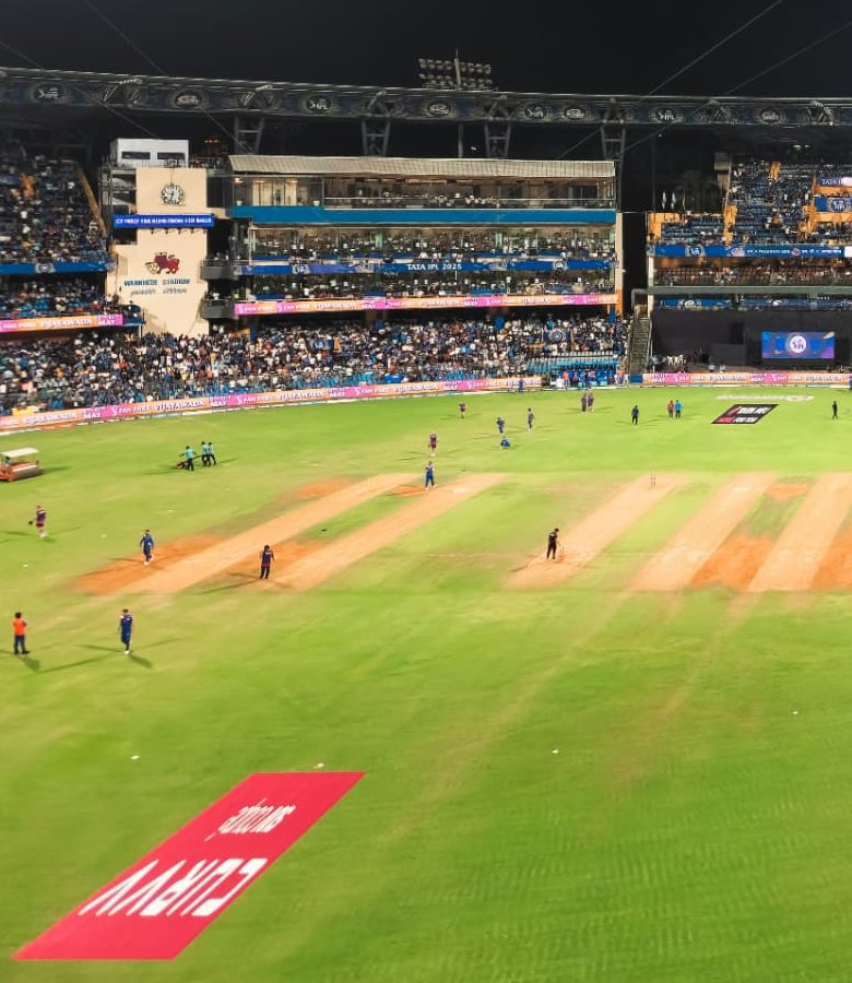 A packed cricket stadium under floodlights at night