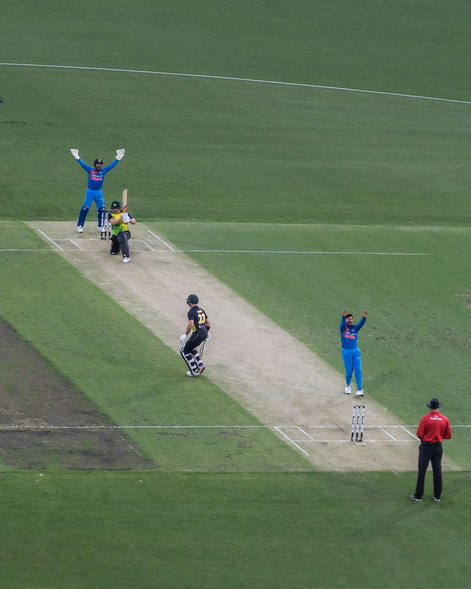 Elevated view of a cricket match with Indian players appealing for a wicket against an Australian batsman on the pitch